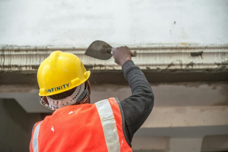 A construction worker in safety gear renovating an interior wall in Delhi, India.