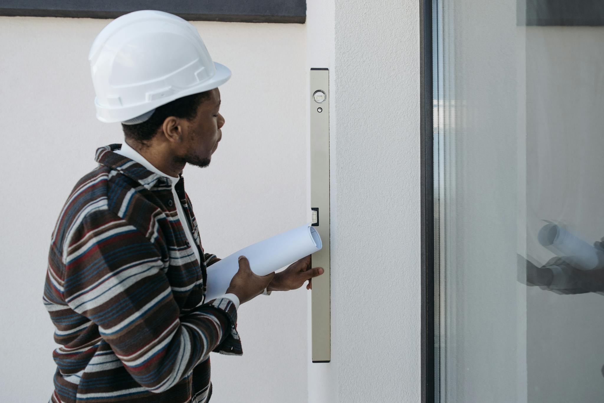 Architect using a level for construction checks, wearing safety helmet.